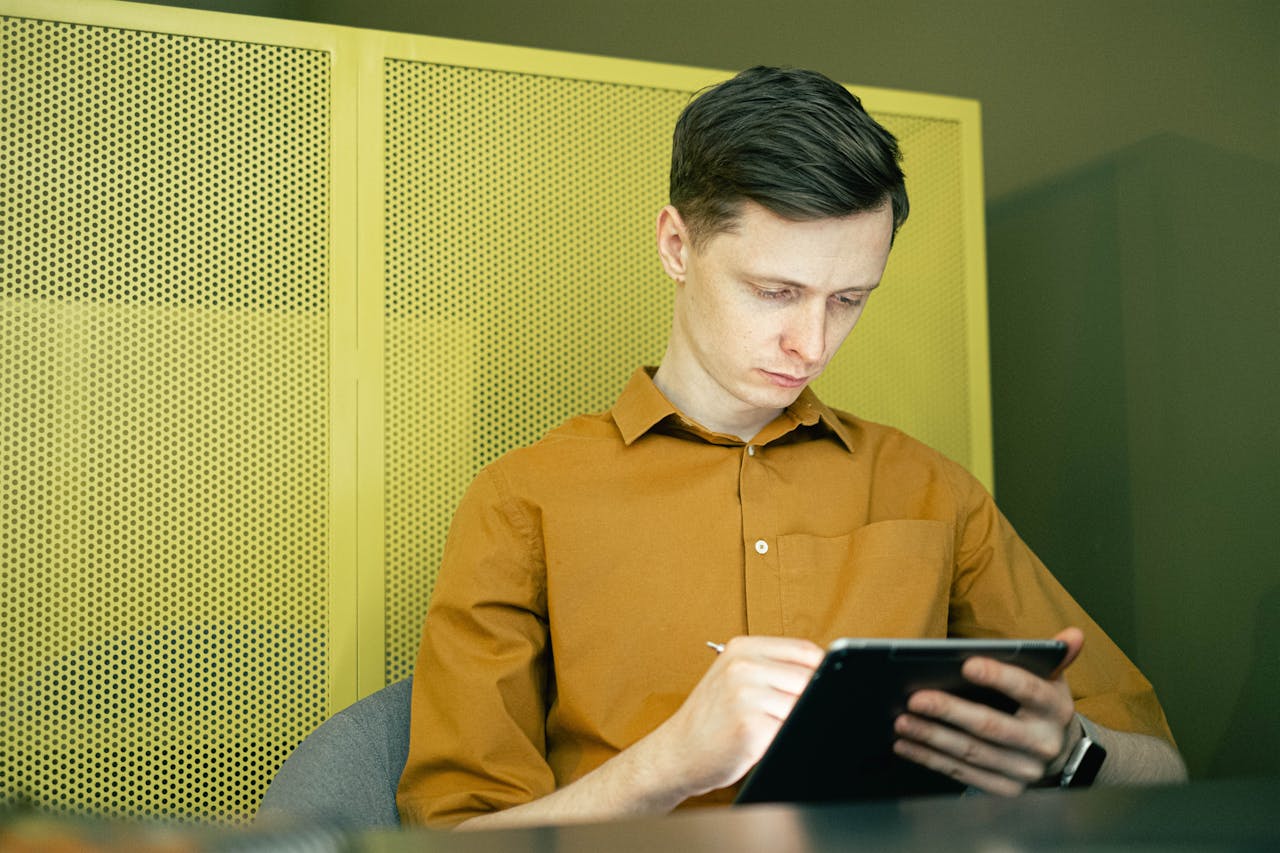 Man using tablet with yellow wall behind